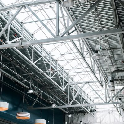 Metal roof structure of a large building, indoors. Built-in windows at the top for lighting, ventilation and lamps. Architecture and construction